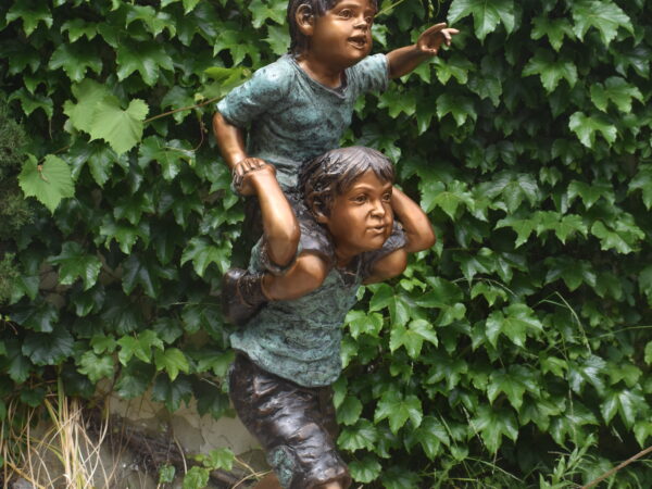 A bronze sculpture of two boys playing.