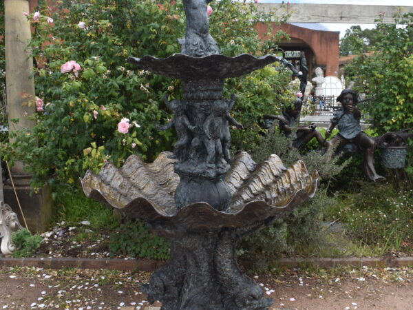 A large bronze fountain featuring a cherubs on clam shell base