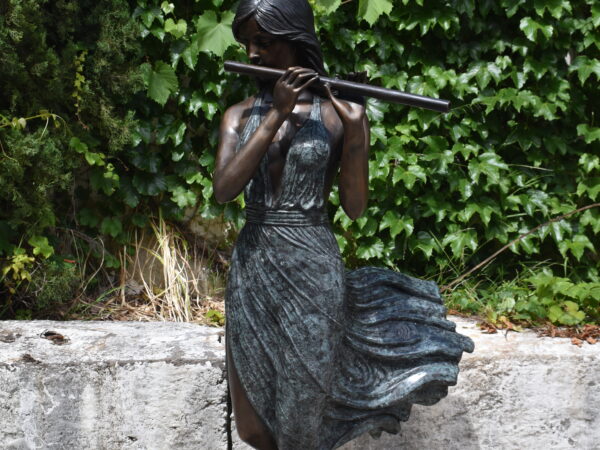 a large bronze statue of a woman playing a flute