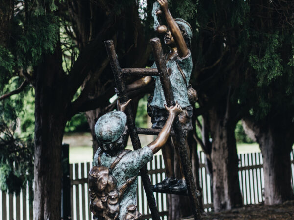 A bronze statue of two boys climbing a ladder