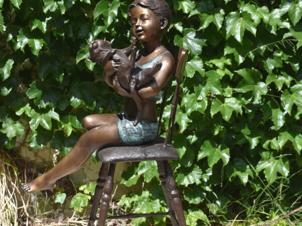 A bronze sculpture of a young girl on a chair