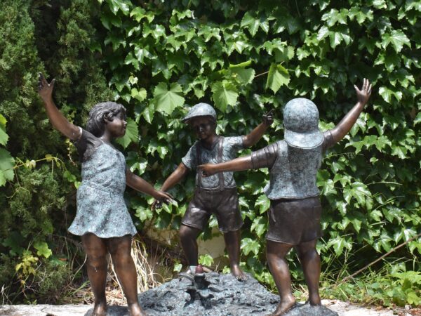 A large bronze statue of 3 children paying ring around the Rosie, plumbed as a fountain water coming from central flower.