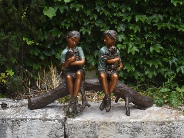 a bronze sculpture of two children on a log