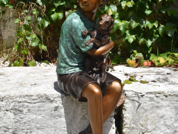 A delightful bronze statue of a young boy playing with a dog
