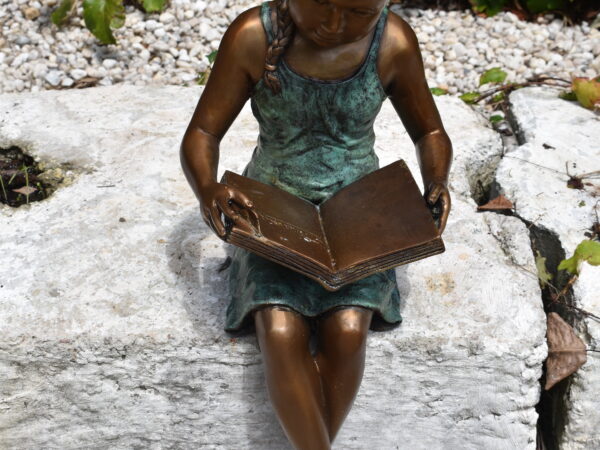 A delightful bronze statue of a young girl reading, 