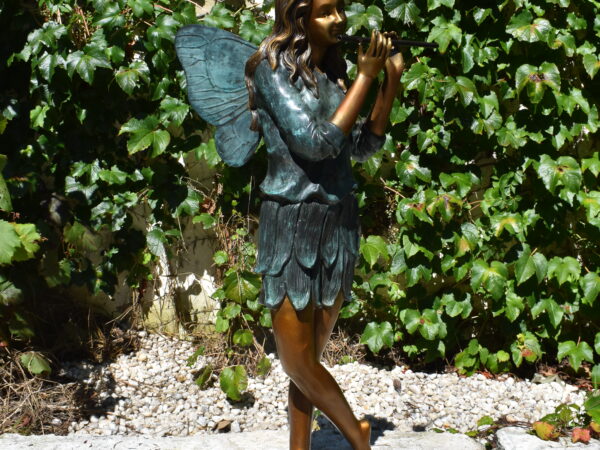 A bronze statue of a fairy playing the flute