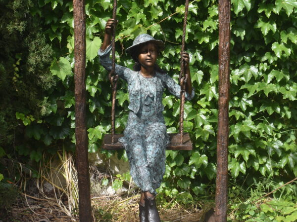 A wonderful bronze of a young boy on a swing.