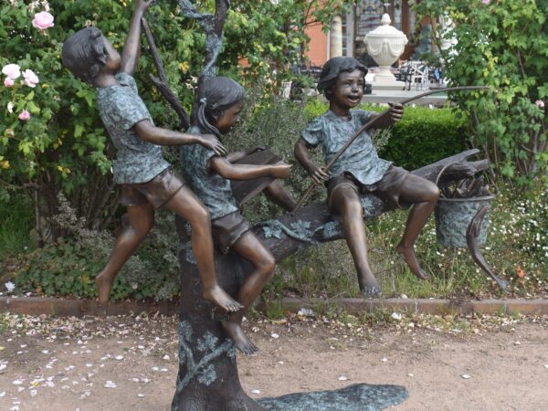 A bronze statue of three children fishing from a tree, plumbed as a fountain. 