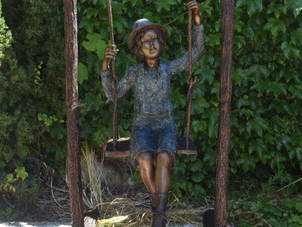 A wonderful bronze of a young boy on a swing.