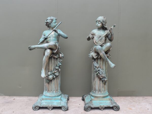 A pair of bronze children playing instrument