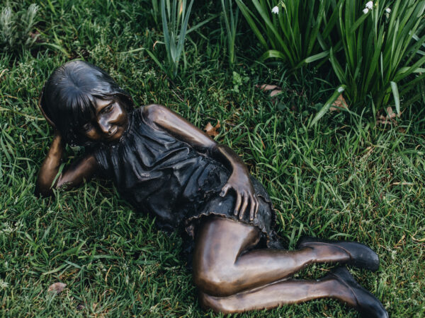 A bronze statue of a young girl at rest
