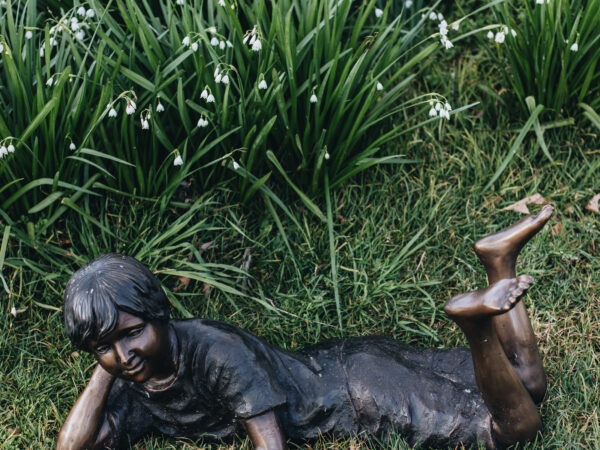 A bronze statue of a young boy at rest.