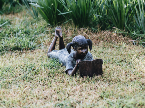 a bronze of a young girl reading 