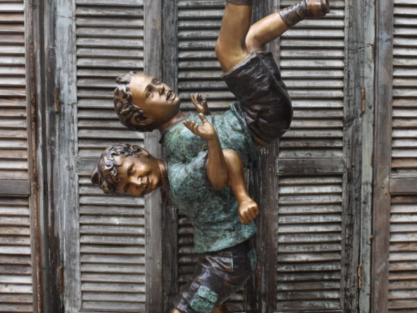 A delightful bronze statue of boys playing piggyback,